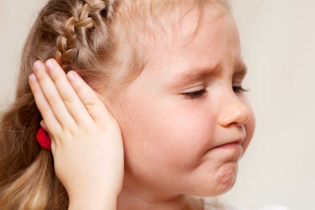 Criança com dor de ouvido coloca a mão na orelha