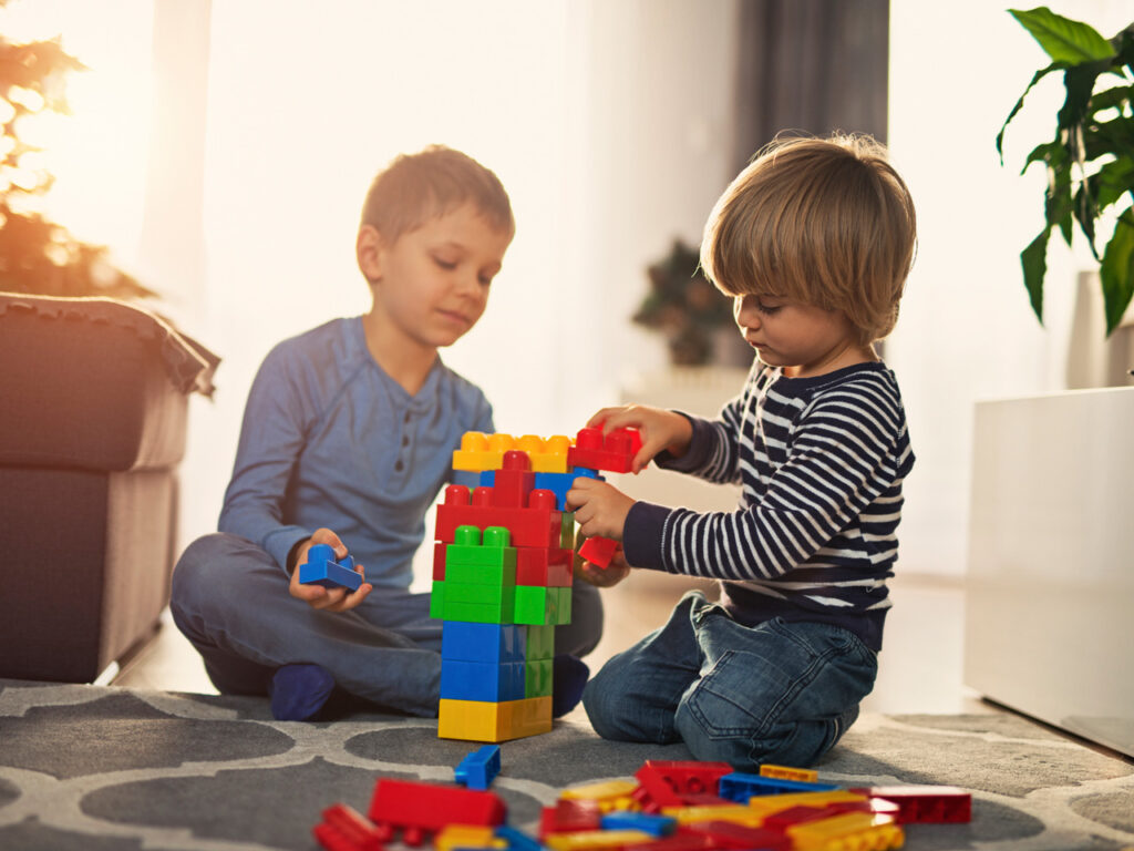 Crianças brincam na sala de casa: jogos estimulam o desenvolvimento infantil
