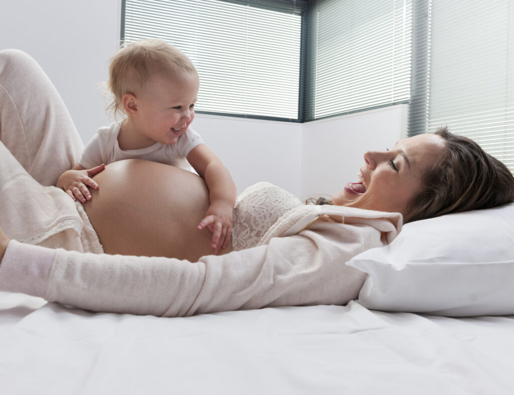 Bebê sorri ao lado da mãe grávida: existe muita controvérsia na literatura médica a respeito da questão: qual o intervalo ideal entre duas gestações?