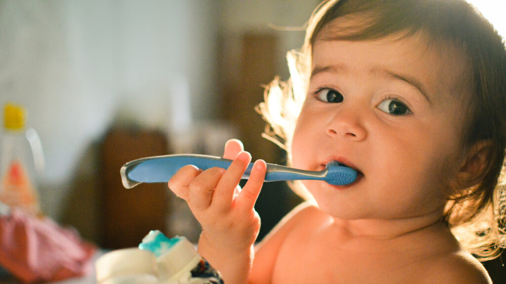Bebê segura escova de dente: é muito importante cuidar da saúde bucal das crianças