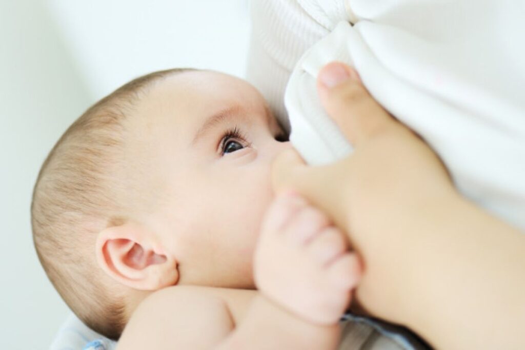 Bebê mamando no seio da mãe; amamentação cruzada: tudo o que você precisa saber!
