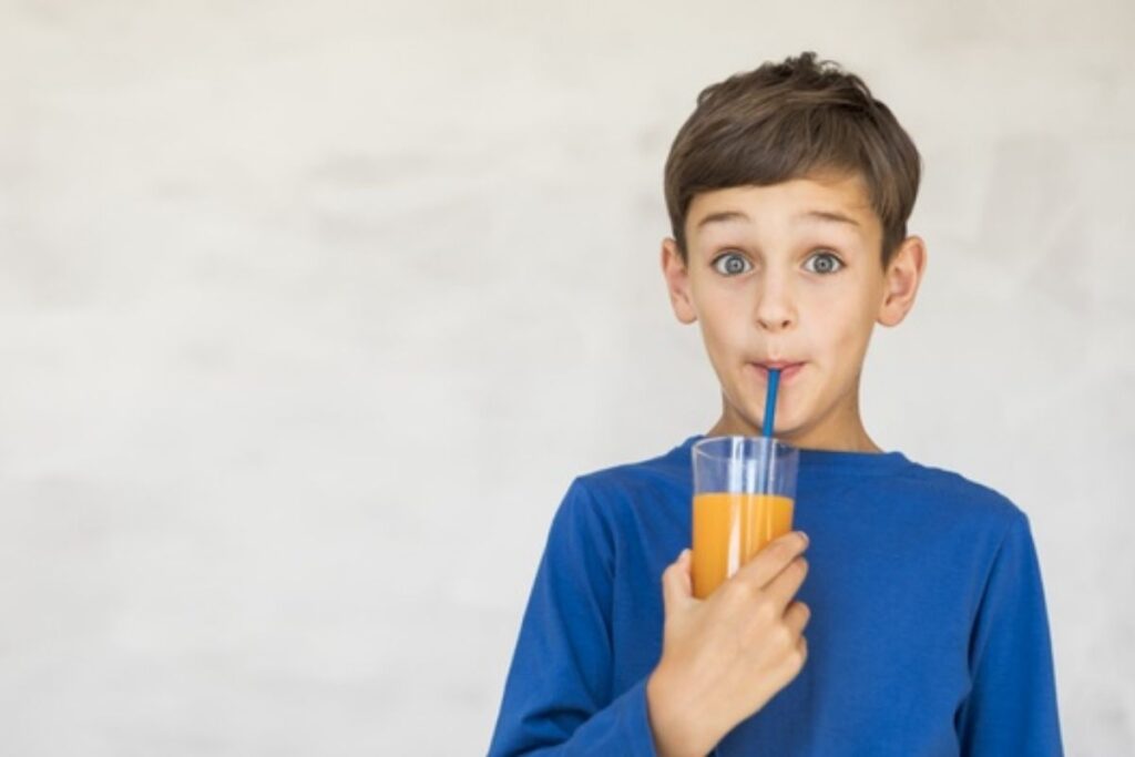 Criança bebe suco com um canudo: ingerir líquidos durante as refeições faz mal?