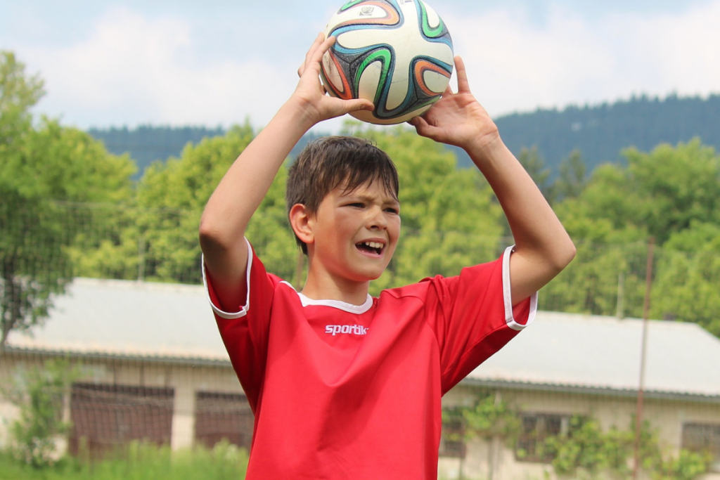 Criança jogando bola; idade relativa: o que é e como pode afetar as crianças?