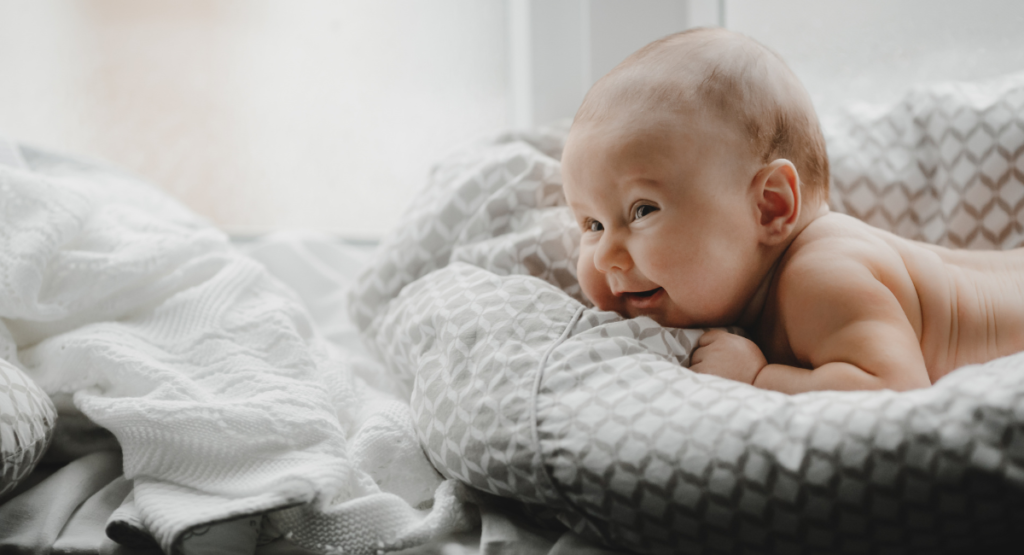 Bebê sorri apoiado em um cobertor: o nascimento de um filho é sempre um momento de muita emoção e ansiedade para os pais.