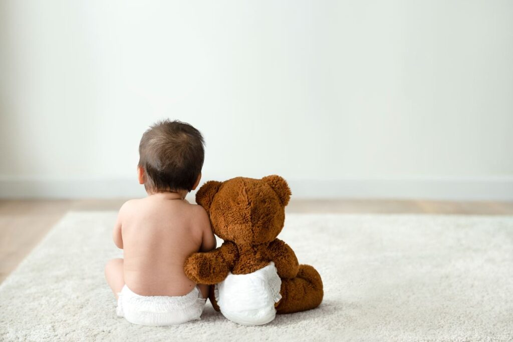 Bebê e urso de pelúcia usando fraldas: saiba como organizar as fraldas do bebê