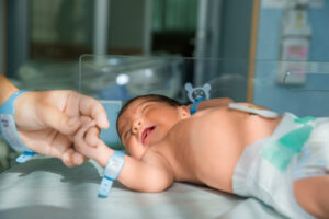 Pai segura a mão do seu bebê recém-nascido: no início da vida, todos os bebês têm o direito de crescerem saudáveis e felizes. É por isso que a expansão do programa de triagem neonatal é fundamental para proteger a saúde dos recém-nascidos.