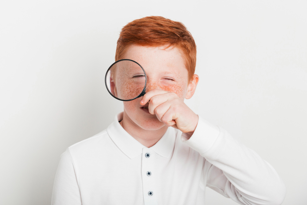 Menino brinca com uma lente de aumento: a catapora é uma infecção viral causada pelo vírus da herpes-zoster que leva ao aparecimento de bolhas vermelhas pelo corpo.